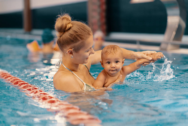 Madre e hijo pequeño divirtiéndose en una piscina
 - Foto, Imagen