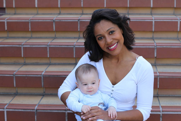 Closeup of mixed race family sitting on stairs. Portrait of mother with newborn  - Photo, Image