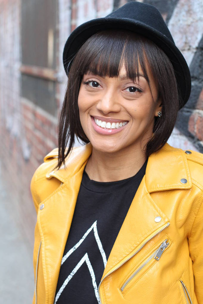 Lifestyle photo shoot portrait of cool trendy stylish sexy hipster African ethnic girl with septum piercing ring. Wearing yellow leather jacket and a hat - Fotoğraf, Görsel