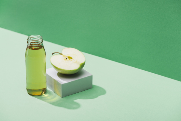 fresh juice near apple half and and white cube on green and turquoise background - Fotoğraf, Görsel