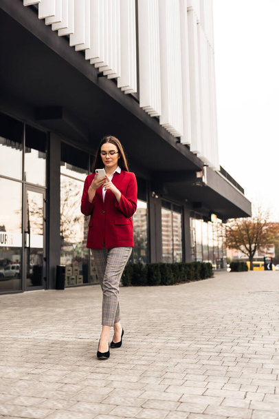 Businesswoman texting messages while walking. - Zdjęcie, obraz