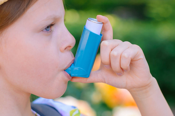 Niña que tiene asma usando inhalador de asma por estar saludable - profundidad de campo superficial - enfoque en inhalador
 - Foto, imagen