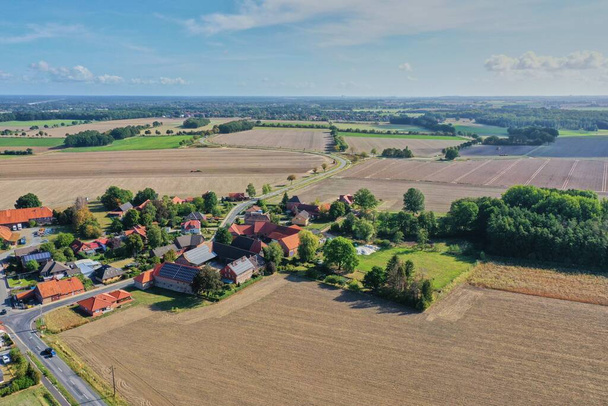 A top view shot of a village in the middle of plowed fields and forests - Foto, Bild
