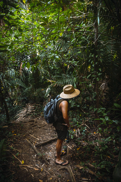 young man with straw hat and backpack in jungle of Tela, Hoduras  - Foto, Imagen
