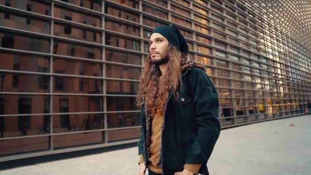Retrato de hipster de pelo largo caminando por la calle en la ciudad moderna
 - Metraje, vídeo