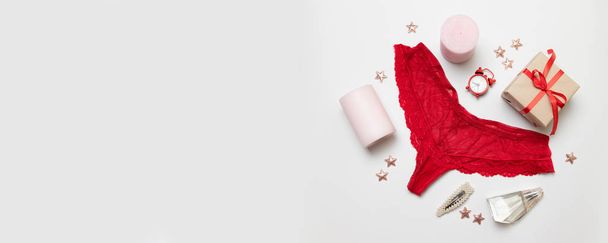 Womens red lace panties, pink candles, perfume, hair clip, red clock alarm, gift box on a gray background - Zdjęcie, obraz