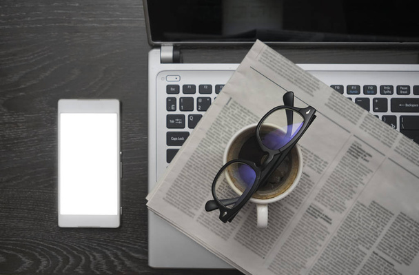 newspaper, mobile cell phone,  laptop, glasses and cup of coffee on wooden table background. empty copy space for inscription - Fotografie, Obrázek