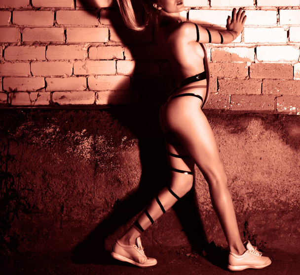 Sexy female semi nude body. young woman posing.  Dramatic shadow on brick wall texture  - 写真・画像