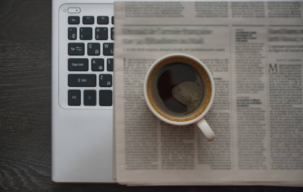 vista dall'alto Immagine di tavolo da lavoro con una tazza di caffè, giornale e laptop. testo sfocato. notizie fresche
.  - Foto, immagini