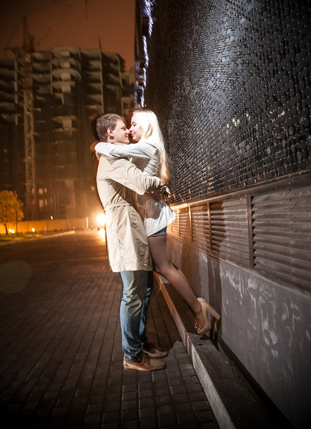 Pareja joven besándose por la noche cerca de la pared negra
 - Foto, imagen