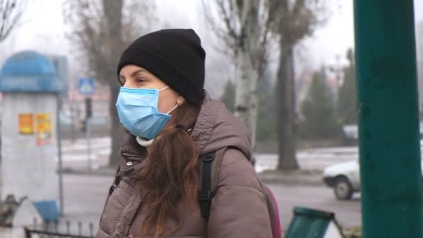 Μια νεαρή γυναίκα βγάζει μια σέλφι με μια προστατευτική ιατρική μάσκα στο δρόμο σε δημόσιο χώρο. Προστασία από τον κινεζικό κορωναϊό. - Πλάνα, βίντεο