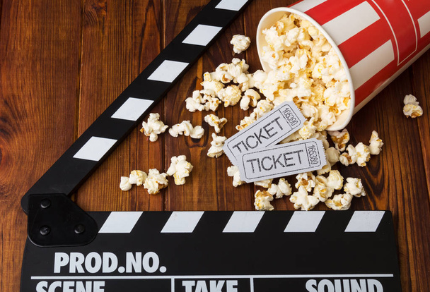 Spilled popcorn, striped box, movie tickets and movie clapper ag - Фото, изображение