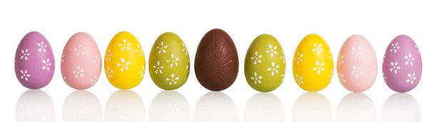 Fila coloridos huevos de Pascua en el centro de chocolate, aislado en blanco
. - Foto, Imagen