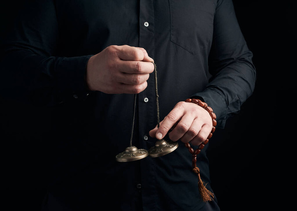 adulto hombre en negro ropa sostiene en sus manos un par de bronce K
 - Foto, imagen