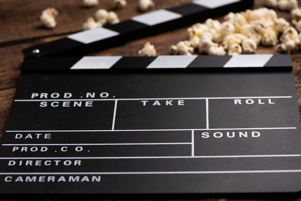 Clapper board and popcorn on wooden background - Photo, Image