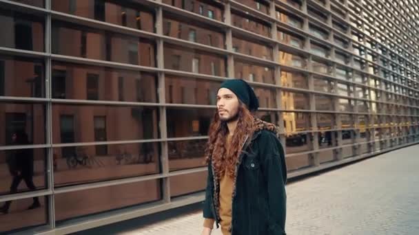 Modern şehirde sokakta yürüyen uzun saçlı hippi portresi. - Video, Çekim