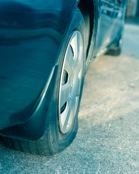 Zadní pohled na píchlou pneumatiku na zeleném autě na příjezdové cestě parkovací garáže zblízka - Fotografie, Obrázek