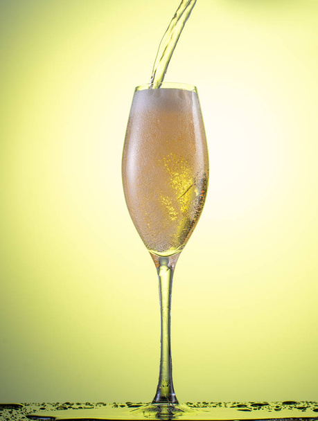 splash in a falling champagne glass on a color yellow gradient background - Foto, immagini