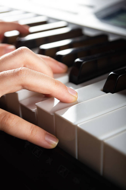 Közelkép a gyermek kezét játszik elektronikus szintetizátor zongora billentyűket. Függőleges fotó zeneboltokhoz, plakátokhoz, reklámfüzetekhez, névjegykártyákhoz, webes prezentációkhoz. A szöveg helye - Fotó, kép