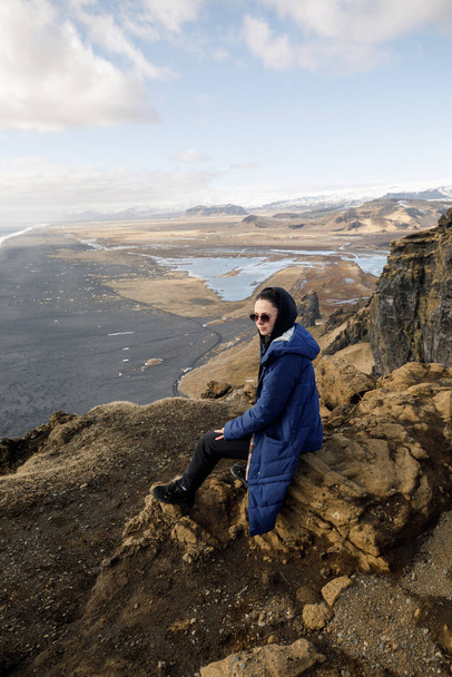 young and pretty woman on cliff on Iceland mountains and Norwegian sea background - Foto, afbeelding