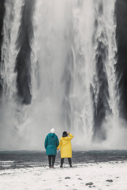 happy and funny couple enjoying big waterfall with in Iceland mountains background - Photo, Image