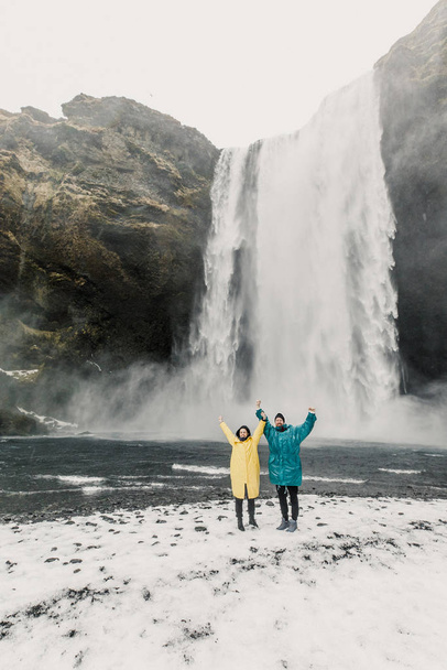 happy and funny couple enjoying big waterfall with in Iceland mountains background - Zdjęcie, obraz