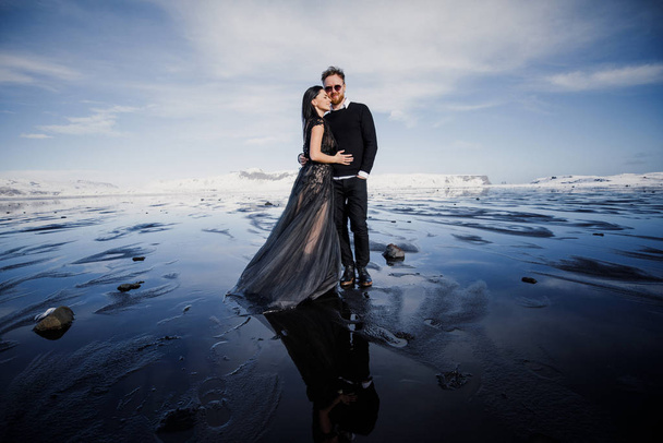 gorgeous young couple posing on frozen black sand beach in Iceland  - Foto, Imagen