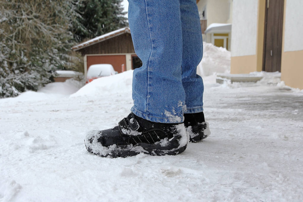 A man in winter boots stands on a snowy road - Photo, Image