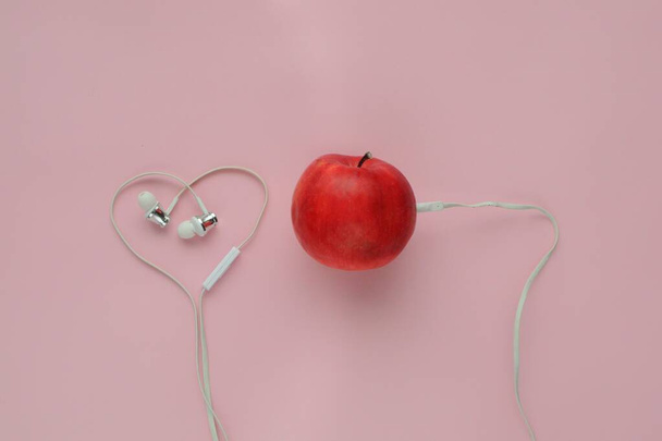 Art flat giaceva su sfondo rosa. Apple con le cuffie. Caricamento musica fresca
. - Foto, immagini