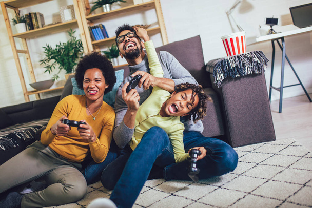 Familia afroamericana en casa sentada en sofá sofá y playin
 - Foto, Imagen