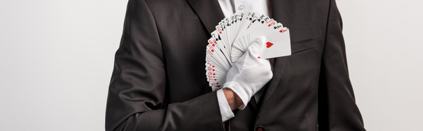 bijgesneden zicht op goochelaar hand speelkaarten, geïsoleerd op grijs, panoramisch schot - Foto, afbeelding