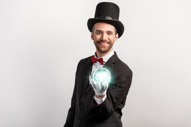 professional magician holding blue magic ball, isolated on grey - Foto, immagini