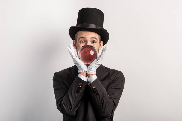 professional magician holding magic ball, isolated on grey - Foto, afbeelding
