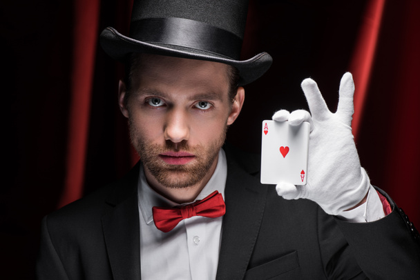 magicien tenant des cartes à jouer dans le cirque avec des rideaux rouges
 - Photo, image