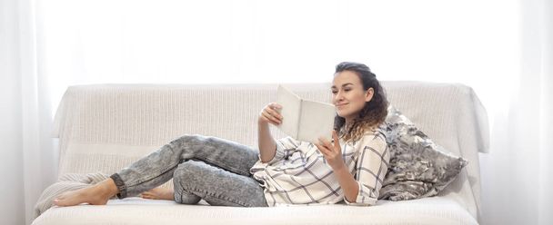 Femme lisant un livre sur le canapé
. - Photo, image