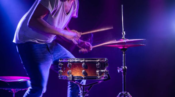 A drummer plays drums on a blue background. Beautiful special ef - Фото, зображення