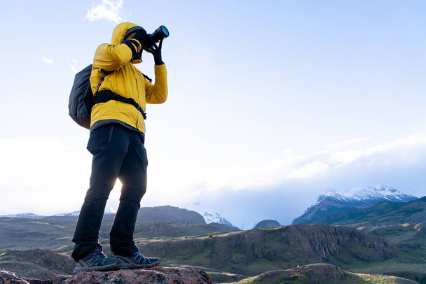Alleen wandelaar met gele jas die foto 's maakt met een camera van de Andes. Patagonië, Argentinië - Foto, afbeelding
