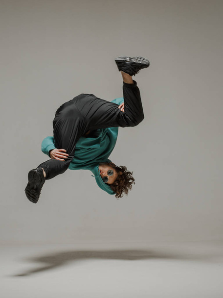Boy dancing breakdance mid-air in studio. Acrobatic dancer. - Foto, Bild