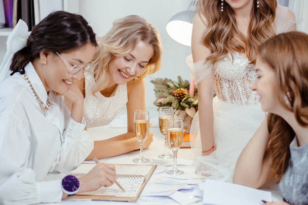 klanten bruiden en ontwerper in trouwsalon - Foto, afbeelding