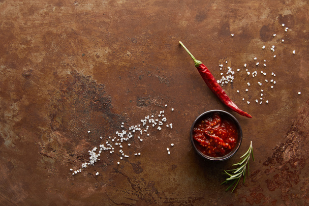 Вид сверху на томатный соус в миске с перцем чили, эмалью и солью на косточке
 - Фото, изображение