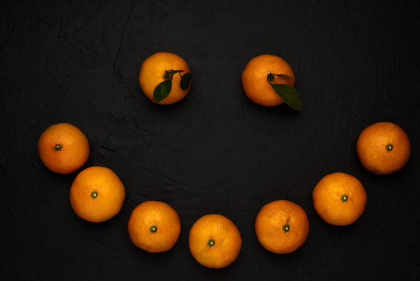 Ripe mandarins smiley on black background - Φωτογραφία, εικόνα