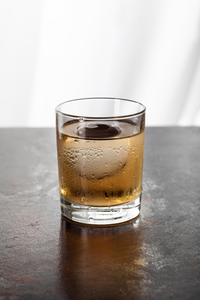 wet glass with whiskey and ice cube on white  - Valokuva, kuva
