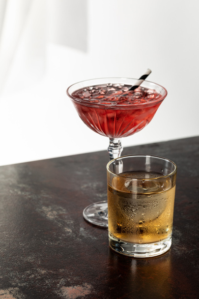 glass of whiskey near red cosmopolitan cocktail on white  - Foto, Imagem