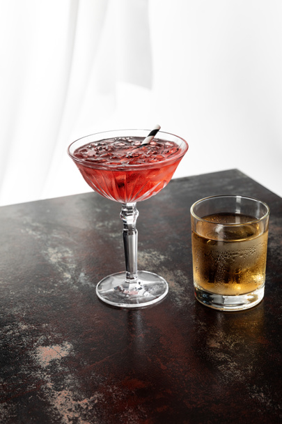 glass of whiskey near cosmopolitan cocktail with ice cubes on white  - Zdjęcie, obraz