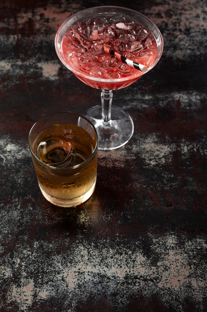 vrchní pohled na kosmopolitní koktejl u skla s whisky na černém povrchu  - Fotografie, Obrázek