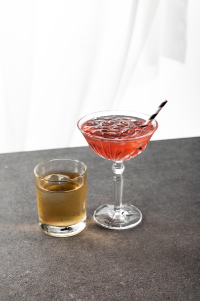 bicchiere con whisky vicino a cocktail cosmopolita rosso e paglia su bianco
 - Foto, immagini