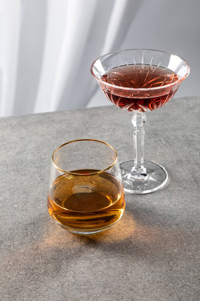 Glas Cognac in der Nähe von Rotwein auf Weiß  - Foto, Bild