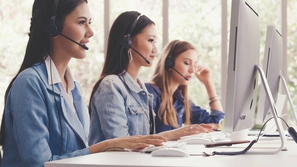Customer support agent or call center with headset works on desktop computer while supporting the customer on phone call. Operator service business representative concept. - 写真・画像