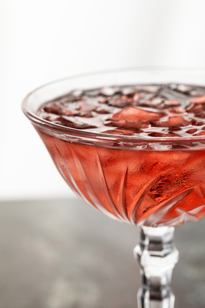 close up of red cocktail with frozen ice cubes in glass on white  - Foto, Bild