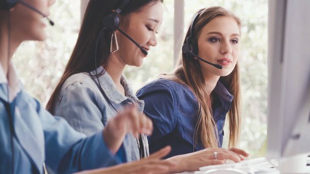 Customer support agent or call center with headset works on desktop computer while supporting the customer on phone call. Operator service business representative concept. - Photo, Image